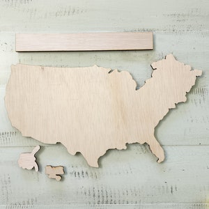 May include: A wooden cutout of the United States of America with separate cutouts for Alaska and Hawaii. The map is on a light green wood background.