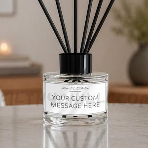Op de afbeelding: Een glazen diffuserfles met een zwarte dop en zes zwarte rietjes. De fles is voorzien van een wit rechthoekig etiket met de tekst "Artisanal Scent Collection" en "YOUR CUSTOM MESSAGE HERE" in zwarte letters op de voorzijde van de fles.