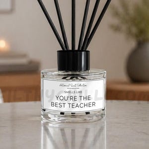 May include: A clear glass reed diffuser bottle with a black cap and six black reeds. The white rectangular label features the text "Artisanal Scent Collection" and "SMELLS LIKE YOU'RE THE BEST TEACHER" in black lettering with a thin black border.
