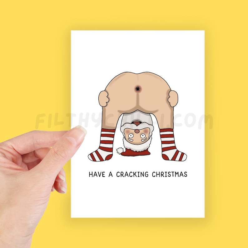 May include: A white Christmas card featuring a cartoon Santa Claus bent over, with his backside visible. Santa's legs are in red and white striped socks. The text "HAVE A CRACKING CHRISTMAS" is printed below the illustration.