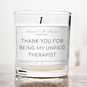 Peut inclure: Un bocal à bougie en verre transparent avec une étiquette blanche qui indique "Antisocial Candle Collection" et "Merci d'être mon thérapeute non payé". L'étiquette comprend également "Notes de : Gratitude" et "25HR".