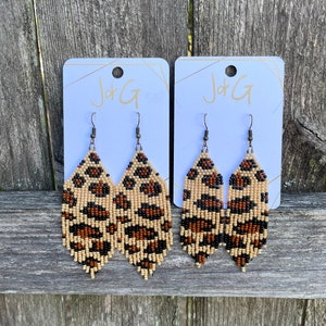 May include: Two pairs of leopard print beaded earrings on white cards with the text "J+G" printed on them.