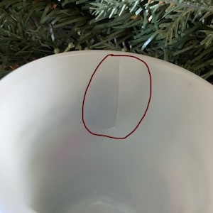 May include: White ceramic mug with a red circle drawn on the inside of the mug.