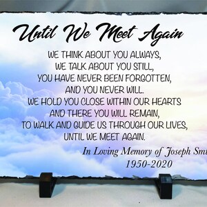 May include: A slate plaque with a poem about remembering a loved one. The poem reads "Until We Meet Again" and includes the text "We think about you always, We talk about you still, You have never been forgotten, And you never will. We hold you close within our hearts And there you will remain, To walk and guide us through our lives, Until we meet again." The plaque also includes the text "In Loving Memory of Joseph Smith 1950-2020". The plaque is set against a background of a cloudy sky.