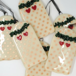 May include: Six cream-colored glass ornaments with a white polka dot pattern and red hearts. Each ornament has a green garland with a red heart at the top.