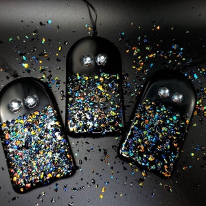 May include: Three black glass ghost ornaments with iridescent glitter embedded in the glass. Each ghost has two white eyes.