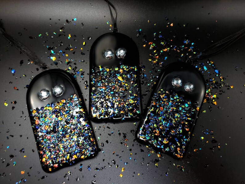 May include: Three black glass ghost ornaments with iridescent glitter embedded in the glass. Each ghost has two white eyes.