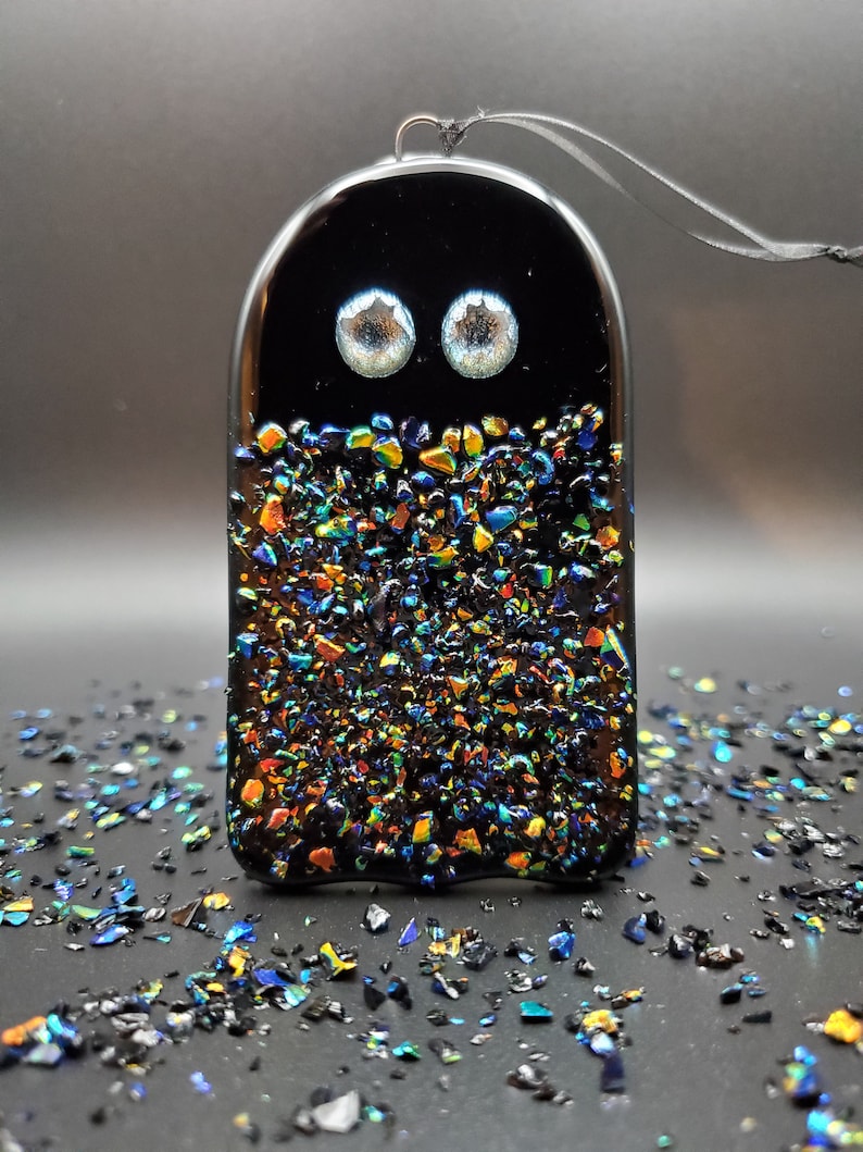 May include: Black glass ghost ornament with iridescent glitter and two white eyes.