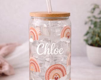 May include: A clear glass tumbler with a bamboo lid and a glass straw. The exterior features a repeating pattern of orange and red rainbows with white clouds and small hearts. The name Chloe is printed in white script in the center.