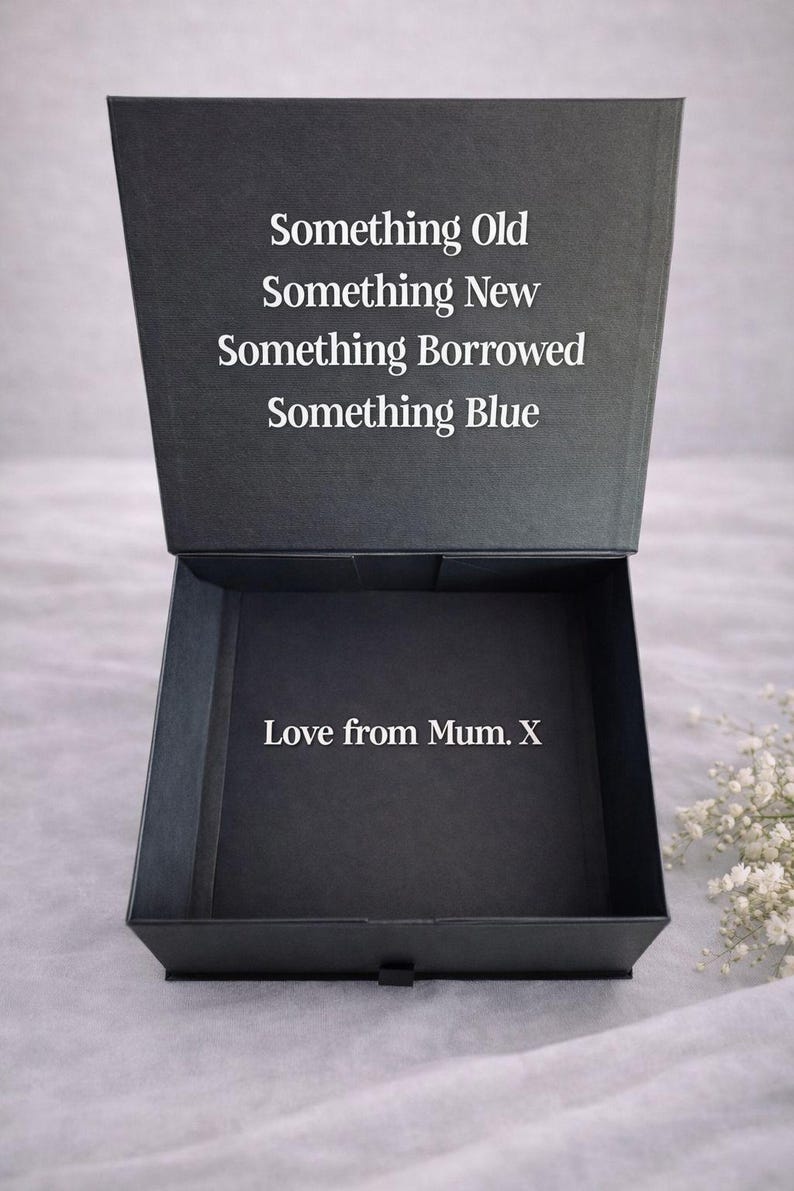 May include: A black square gift box with a hinged lid. The inside of the lid features the white text: Something Old, Something New, Something Borrowed, Something Blue. The bottom interior of the box displays the white text: Love from Mum. X.