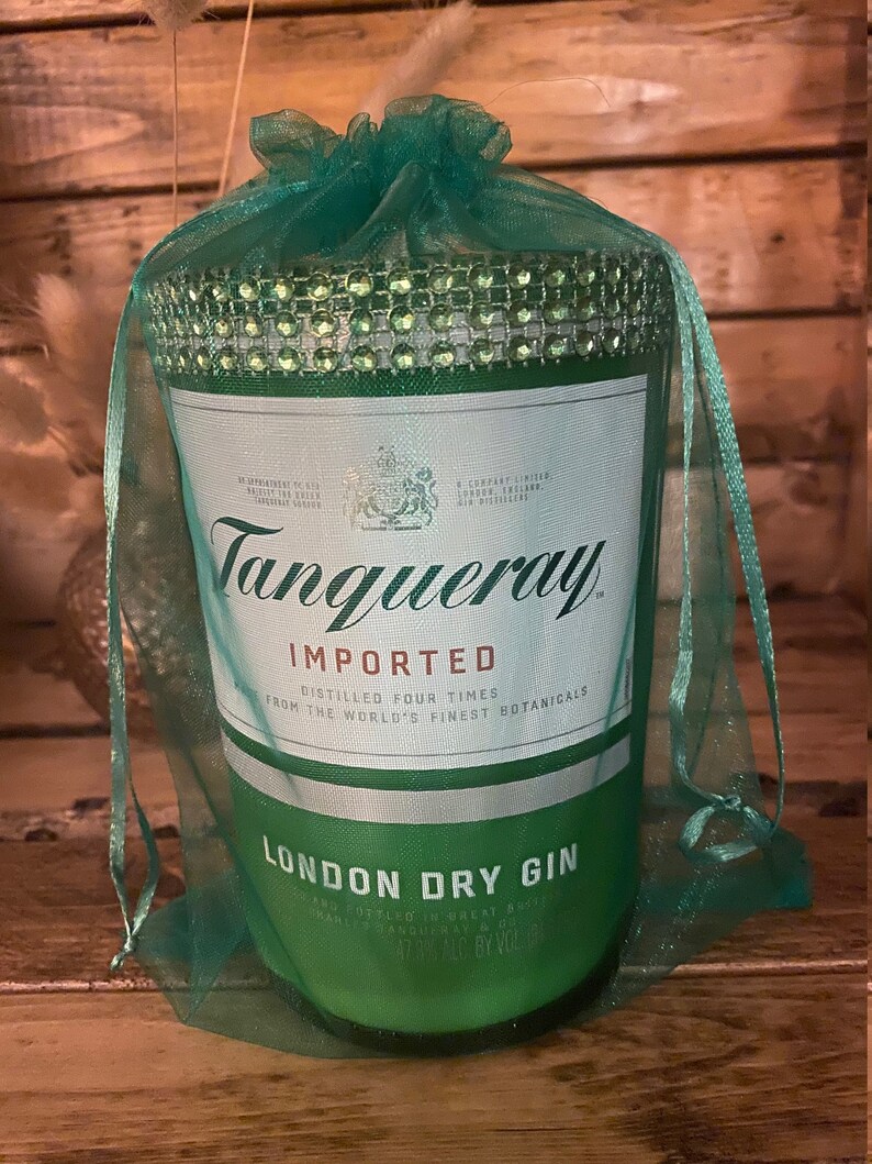 May include: A green glass bottle of Tanqueray London Dry Gin, wrapped in a green tulle bag with rhinestones. The bottle label reads "Tanqueray Imported, Distilled Four Times from the World's Finest Botanicals, London Dry Gin".