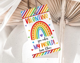 May include: A rectangular Valentine's Day gift tag with a rainbow design and the text "VALENTINE you color MY WORLD!" in colorful letters. The tag has a rainbow border and is tied with a brown string.