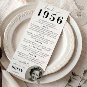 May include: A white card with black text, placed on a white plate, lists facts from 1956, including news, music, movies, and prices. A small photo of a child is at the bottom. The text reads "back in 1956".
