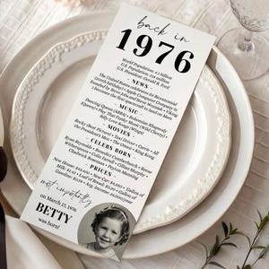 May include: A white paper menu on a white plate, with the text "back in 1976" and a list of facts from that year. Includes a photo of a young girl and the text "BETTY was born!"