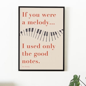 May include: A framed art print with the text "If you were a melody... I used only the good notes." The artwork features a piano keyboard design and is in a black frame. A decorative lamp and plant are in the foreground.