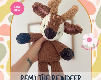 May include: A handmade crochet reindeer toy in shades of brown, white, and black. The reindeer has large antlers, a dark nose, and a friendly expression. The text "Remi the Reindeer Crochet Pattern" is displayed at the bottom.
