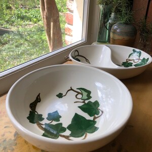 May include: Two white ceramic bowls with a green ivy design. The larger bowl is divided into two sections.