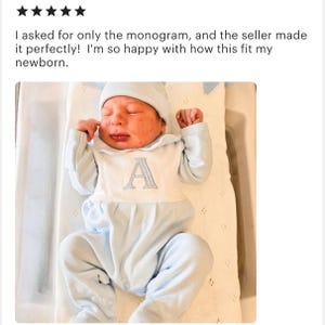May include: A newborn baby wearing a light blue onesie and matching cap. The onesie features a white bib with a gray embroidered letter "A". The text above the baby reads: "I asked for only the monogram, and the seller made it perfectly! I'm so happy with how this fit my newborn."