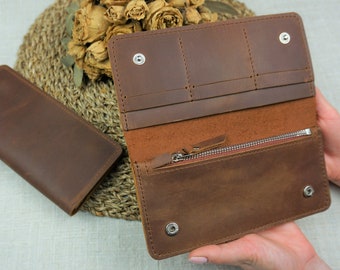 May include: A brown leather wallet with multiple card slots and a zippered compartment. The wallet is open and the interior is visible.