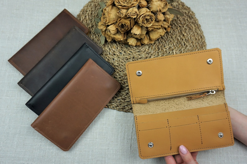 Puede incluir: Cuatro carteras de cuero en diferentes colores, incluyendo marr&oacute;n, negro y beige. Las carteras est&aacute;n dispuestas en una pila, con la beige en la parte superior. Las carteras est&aacute;n todas cerradas, y la beige est&aacute; abierta para mostrar el interior.