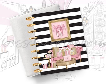May include: A white and black striped planner with gold rings. The planner has a pink and gold design with a pair of pink high heels, gift boxes, and a pink sofa. The planner is open to a page with a black and white striped background.
