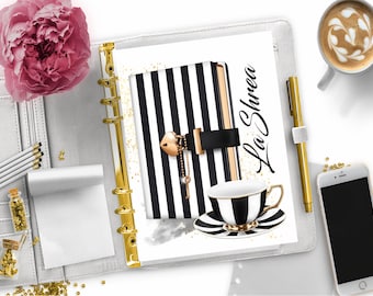May include: A white and black striped notebook with a gold lock and key charm. The notebook is open to a page with gold glitter and the text "La Shree". A black and white teacup and saucer are on the page.