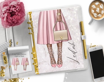 May include: A white planner with a gold ring binder and a pink and white illustration of a woman wearing a pink skirt, black and white polka dot stockings, and black heels. The planner has the name "Leilah" written on it.