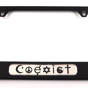 May include: Black license plate frame with the word "Coexist" and symbols representing different religions and beliefs. The frame is rectangular with mounting holes and a silver accent.