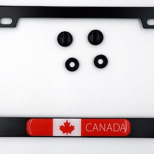 May include: Black license plate frame featuring the Canadian flag and the word "CANADA" in white. Includes four black mounting hardware pieces. The frame is rectangular and made of metal.