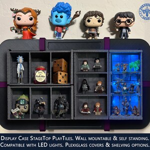 Puede incluir: Una vitrina negra con múltiples compartimentos para exhibir figuras y otros objetos de colección. La vitrina tiene un borde morado y está etiquetada con "DISPLAY CASE STAGETOP PLAYTILES. WALL MOUNTABLE & SELF STANDING. COMPATIBLE WITH LED LIGHTS. PLEXIGLASS COVERS & SHELVING OPTIONS."
