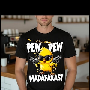 Puede incluir: Camiseta negra con un gráfico de un pollito amarillo con gafas de sol y sosteniendo dos pistolas. El texto "PEW PEW MADAFAKAS!" está impreso encima y debajo del pollito.