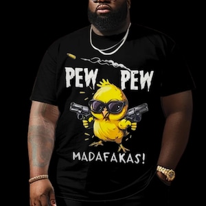 May include: Black t-shirt featuring a cartoon yellow chick wearing sunglasses and holding two guns. The text "PEW PEW MADAFAKAS!" is printed above and below the chick illustration. The image is set against a dark background.