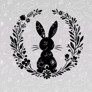 May include: Black silhouette of a rabbit sitting inside a wreath of black floral designs. The background is a light gray with white doodle-like designs.