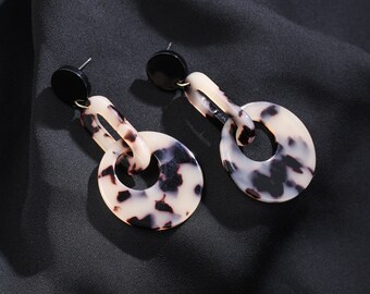 May include: A pair of black and white patterned earrings with a black accent. The earrings are made of a lightweight material and have a unique design.