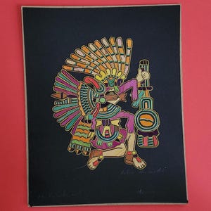 May include: A colorful embroidered artwork on black fabric. The image depicts a figure in traditional attire, holding a staff. The artwork features vibrant hues of orange, yellow, green, purple, and pink. The artwork is framed and set against a red background.