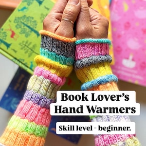 Könnte beinhalten: Gestrickte Handstulpen mit Regenbogenstreifen und grauen Bündchen. Der Text "Book Lover's Hand Warmers" und "Skill level - beginner" sind zu sehen. Bücher mit bunten Einbänden sind im Hintergrund.