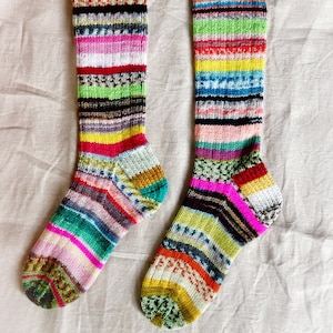 Puede incluir: Un par de calcetines de rayas de colores hasta la rodilla con una variedad de colores que incluyen rosa, verde, amarillo, azul y negro.