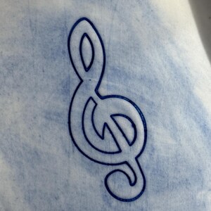 May include: A blue treble clef design on a light blue and white background. The musical symbol is a dark blue outline, with a textured, watercolor-like effect in the background.