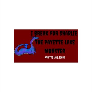 May include: A maroon rectangle with the text "I BREAK FOR SHARLIE THE PAYETTE LAKE MONSTER PAYETTE LAKE, IDAHO." A blue and purple cartoon sea serpent is on the left side of the rectangle.
