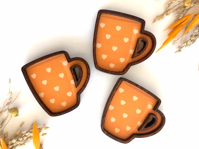 May include: Three wooden mugs with a brown rim and a light orange background with white hearts.