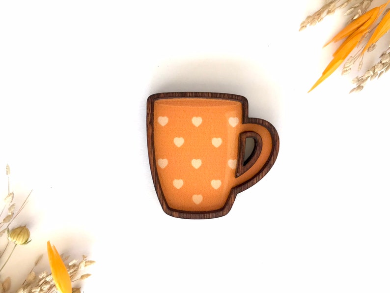 May include: A wooden mug with a brown rim and handle. The mug is painted orange with white hearts.