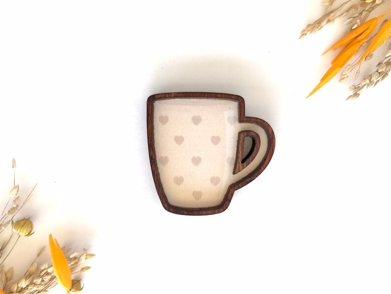 May include: A wooden mug with a brown rim and a white interior with a pattern of small hearts. The mug is a decorative item.