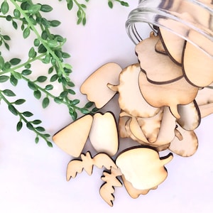 May include: A glass jar filled with various wooden shapes, including leaves, flowers, and other organic forms. The shapes are unfinished and ready to be painted or decorated.