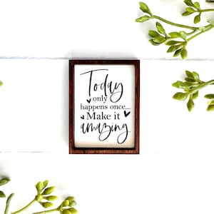 May include: A wooden sign with a brown frame and white background. The sign says "Today only happens once... Make it amazing" with small hearts around the text.