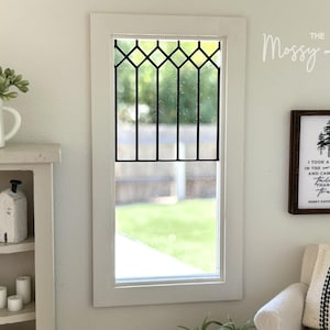 May include: A miniature room scene featuring a white-framed window with a black diamond-patterned grid. To the right, a framed sign displays a tree illustration and the text: I TOOK A WALK IN THE WOODS AND CAME OUT TALLER THAN THE TREES HENRY DAVID THOREAU.