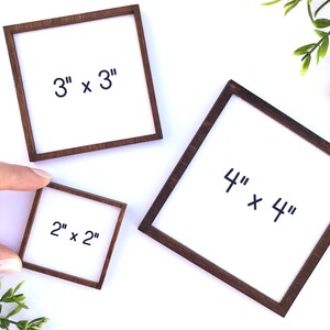 May include: Three square wooden frames with white centers. The frames are different sizes: 2" x 2", 3" x 3", and 4" x 4". Each frame has dark brown wooden borders. The text "2" x 2"", "3" x 3"", and "4" x 4"" is written in black on the white centers.