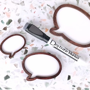 May include: Three speech bubble-shaped whiteboards with dark brown wooden frames of varying sizes, accompanied by a black and white dry erase marker with the text Dry Erase Marker for Whiteboards printed on the barrel.