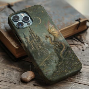 May include: A smartphone case featuring a detailed illustration of a golden dragon perched on a rocky cliffside next to a tall castle. The scene is set against a dark green background with a crescent moon and small stars scattered across the night sky.