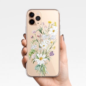 May include: A clear phone case with a gold trim and a watercolor design of white flowers and green leaves.