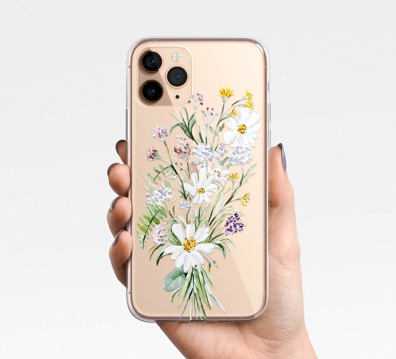 May include: A clear phone case with a gold trim and a watercolor design of white flowers and green leaves.